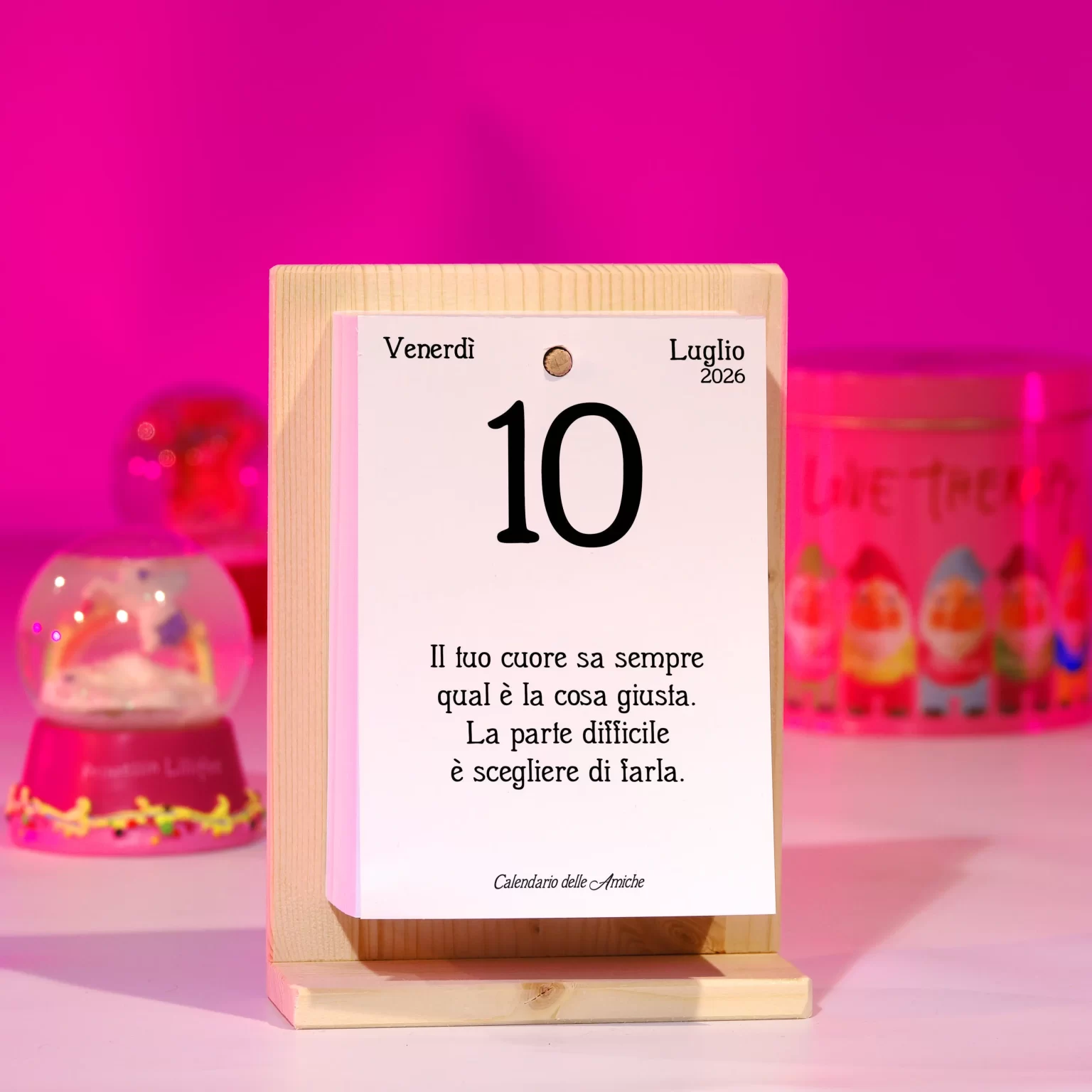Calendario con sfondo rosa e souvenir con palla di vetro e neve